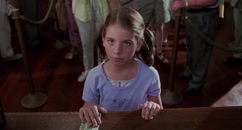 Movie still from “Men in Black II” (2002), directed by Barry Sonnenfeld – A little girl sitting in front of a wooden table; Close Up shot, Over the shoulder angle