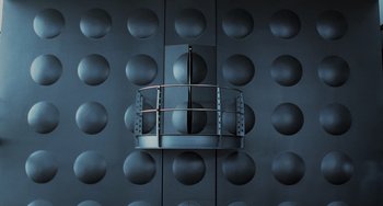 Movie still from “Men in Black II” (2002), directed by Barry Sonnenfeld – A black wall that has some holes in it; Extreme Wide shot, Low angle