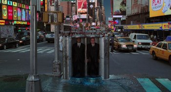 Movie still from “Men in Black II” (2002), directed by Barry Sonnenfeld – Two men in suits standing in an elevator in the middle of a city; Extreme Wide shot, High angle