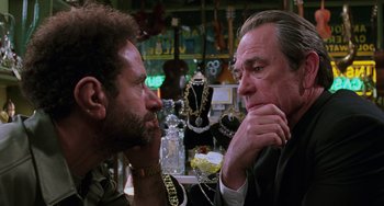 Movie still from “Men in Black II” (2002), directed by Barry Sonnenfeld – Two men are sitting at a table in a jewelry store; Close Up shot, Over the shoulder angle