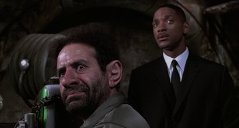 Movie still from “Men in Black II” (2002), directed by Barry Sonnenfeld – A man and a man in a suit and tie; Medium shot, Low angle