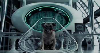Movie still from “Men in Black II” (2002), directed by Barry Sonnenfeld – A dog sitting on top of a chair in a room; Medium shot, High angle