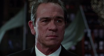 Movie still from “Men in Black II” (2002), directed by Barry Sonnenfeld – An older man in a suit and tie looking at the camera; Close Up shot, Low angle