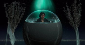 Movie still from “Men in Black II” (2002), directed by Barry Sonnenfeld – A woman sitting inside of an aquarium in a dark room; Wide shot, High angle