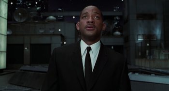 Movie still from “Men in Black II” (2002), directed by Barry Sonnenfeld – A man in a suit and tie looking upward; Medium shot, Low angle
