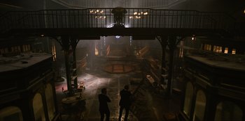 Movie still from “Men in Black: International” (2019), directed by F. Gary Gray – Two people are standing in a dark room; Extreme Wide shot, High angle