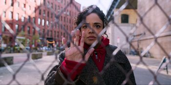 Movie still from “Men in Black: International” (2019), directed by F. Gary Gray – A young woman holding her hand up in front of a fence; Close Up shot, High angle