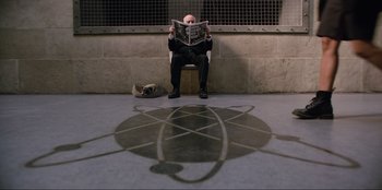 Movie still from “Men in Black: International” (2019), directed by F. Gary Gray – A man sitting on the ground reading a newspaper; Wide shot, High angle