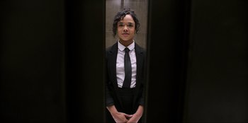 Movie still from “Men in Black: International” (2019), directed by F. Gary Gray – A woman wearing a suit and tie standing in front of an elevator; Medium shot, Low angle