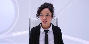 Movie still from “Men in Black: International” (2019), directed by F. Gary Gray – A woman wearing a suit and tie sitting in a chair; Close Up shot, High angle
