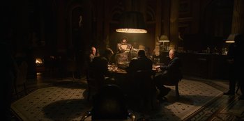 Movie still from “Men in Black: International” (2019), directed by F. Gary Gray – A group of people sitting around a table in a room; Wide shot, High angle