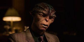 Movie still from “Men in Black: International” (2019), directed by F. Gary Gray – A man in a suit and tie with a strange mask on his face; Close Up shot, High angle
