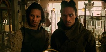 Movie still from “Men in Black: International” (2019), directed by F. Gary Gray – A couple of men standing next to each other in a room; Close Up shot, Over the shoulder angle