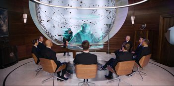 Movie still from “Men in Black: International” (2019), directed by F. Gary Gray – A group of people sitting in a room; Wide shot, Over the shoulder angle