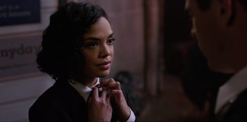 Movie still from “Men in Black: International” (2019), directed by F. Gary Gray – A woman in a suit adjusting her neck tie; Close Up shot, Over the shoulder angle