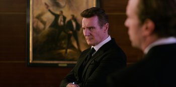 Movie still from “Men in Black: International” (2019), directed by F. Gary Gray – A man wearing a suit and tie in front of a painting; Close Up shot, Over the shoulder angle