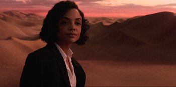 Movie still from “Men in Black: International” (2019), directed by F. Gary Gray – A woman standing in front of a desert landscape at sunset; Medium shot, Over the shoulder angle