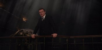 Movie still from “Men in Black: International” (2019), directed by F. Gary Gray – A man wearing a suit and tie standing next to a railing; Medium shot, Low angle