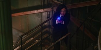Movie still from “Men in Black: International” (2019), directed by F. Gary Gray – A woman in a suit and tie holding a gun in her hand; Medium shot, High angle