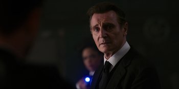 Movie still from “Men in Black: International” (2019), directed by F. Gary Gray – A man wearing a suit and tie with a flashlight in the background; Close Up shot, Over the shoulder angle