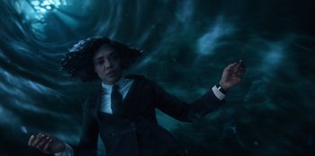 Movie still from “Men in Black: International” (2019), directed by F. Gary Gray – A person in a suit and tie in a dark room; Medium shot, Overhead angle