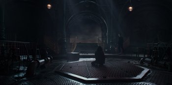 Movie still from “Men in Black: International” (2019), directed by F. Gary Gray – A person sitting on the ground in front of a staircase; Extreme Wide shot, High angle