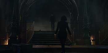 Movie still from “Men in Black: International” (2019), directed by F. Gary Gray – A woman walking down a set of stairs with a man standing at the top of the steps; Wide shot, Low angle