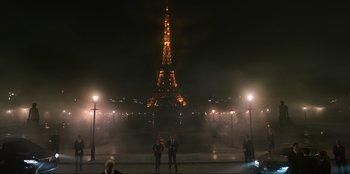 Movie still from “Men in Black: International” (2019), directed by F. Gary Gray – A group of people standing in front of the eiffel tower at night; Extreme Wide shot, Low angle