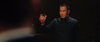 Movie still from “Midway” (2019), directed by Roland Emmerich – A man holding up a glass of whiskey; Close Up shot, Over the shoulder angle