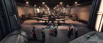 Movie still from “Midway” (2019), directed by Roland Emmerich – A group of men standing in front of airplanes in a hangar; Extreme Wide shot, High angle