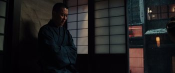 Movie still from “Midway” (2019), directed by Roland Emmerich – A man sitting in front of a window in front of a wall; Medium shot, Low angle