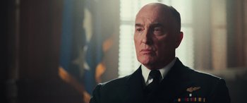 Movie still from “Midway” (2019), directed by Roland Emmerich – An older man wearing a suit and tie; Close Up shot, Low angle