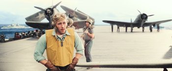 Movie still from “Midway” (2019), directed by Roland Emmerich – A man standing in front of airplanes on a runway; Medium shot, High angle