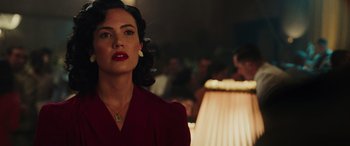 Movie still from “Midway” (2019), directed by Roland Emmerich – A woman in a red dress is standing in front of a lamp; Close Up shot, Over the shoulder angle