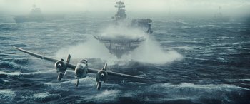 Movie still from “Midway” (2019), directed by Roland Emmerich – An airplane is flying over a large ship in the ocean; Extreme Wide shot, High angle
