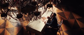 Movie still from “Midway” (2019), directed by Roland Emmerich – A man sitting at a table with a plate of food in front of him; Wide shot, High angle