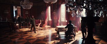 Movie still from “Midway” (2019), directed by Roland Emmerich – A man sitting at a table in front of a large window; Wide shot, High angle