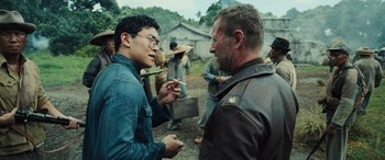 Movie still from “Midway” (2019), directed by Roland Emmerich – Two men standing next to each other on a dirt field; Medium shot, Over the shoulder angle