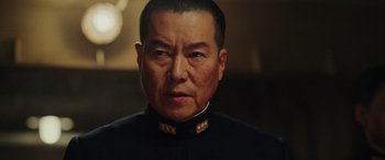 Movie still from “Midway” (2019), directed by Roland Emmerich – An older man wearing a black suit with gold buttons; Close Up shot, Low angle