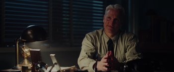 Movie still from “Midway” (2019), directed by Roland Emmerich – An older man sitting at a table in front of a window; Medium shot, Over the shoulder angle