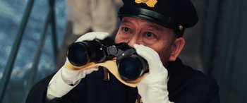 Movie still from “Midway” (2019), directed by Roland Emmerich – A man in a uniform looking through a pair of binoculars; Close Up shot, Low angle
