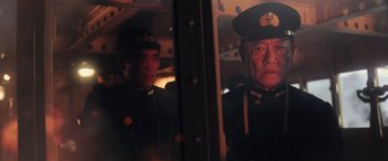Movie still from “Midway” (2019), directed by Roland Emmerich – Two men in uniform are looking out of a train window; Medium shot, Low angle