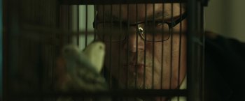 Movie still from “Mindcage” (2022), directed by Mauro Borrelli – A man with glasses is looking through a cage; Extreme Close Up shot, Low angle