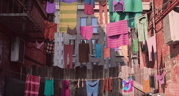 Movie still from “Minions” (2015), directed by Pierre Coffin – Clothes are hanging on a clothes line outside a brick building; Extreme Wide shot, Overhead angle