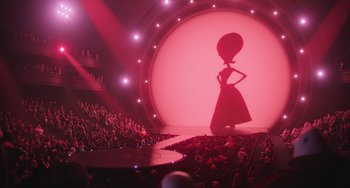 Movie still from “Minions” (2015), directed by Pierre Coffin – A woman is standing in front of an audience in front of a stage; Extreme Wide shot, Over the shoulder angle