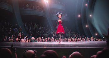 Movie still from “Minions” (2015), directed by Pierre Coffin – A woman in a red dress on a stage in front of an audience; Wide shot, Low angle
