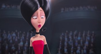 Movie still from “Minions” (2015), directed by Pierre Coffin – A woman in a red dress is standing in front of an audience; Close Up shot, Low angle