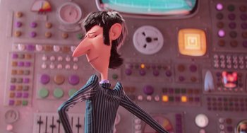 Movie still from “Minions” (2015), directed by Pierre Coffin – A man with long black hair is standing in front of a control panel; Medium shot, Over the shoulder angle