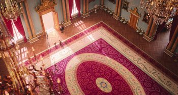 Movie still from “Minions” (2015), directed by Pierre Coffin – A room filled with wooden floors and a large rug on the floor; Extreme Wide shot, High angle