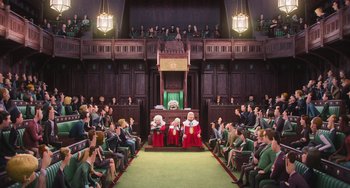 Movie still from “Minions” (2015), directed by Pierre Coffin – A group of people sitting in front of an audience in a courtroom; Extreme Wide shot, Overhead angle